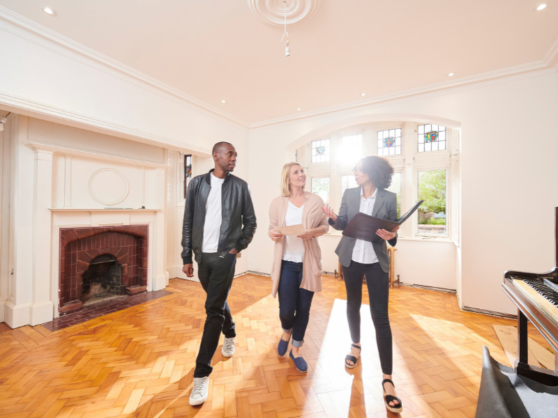 An image of a couple and estate agent looking around a house